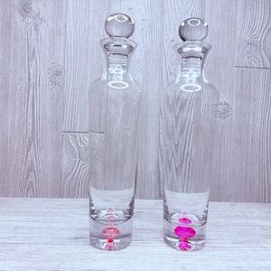 Two tall clear glass decanters with colorful pink / red bubbles bar wear decants
